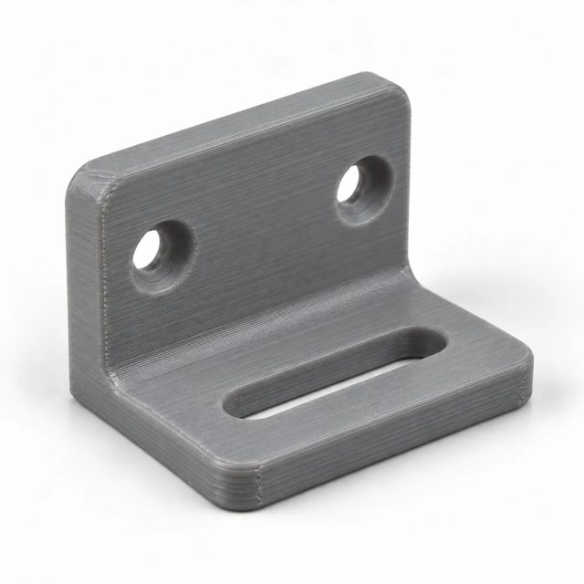 Grauer Befestigungswinkel aus Kunststoff mit zwei Bohrungen und Langloch, im 3D-Druck nachgefertigt, mit feinen Druckschichten