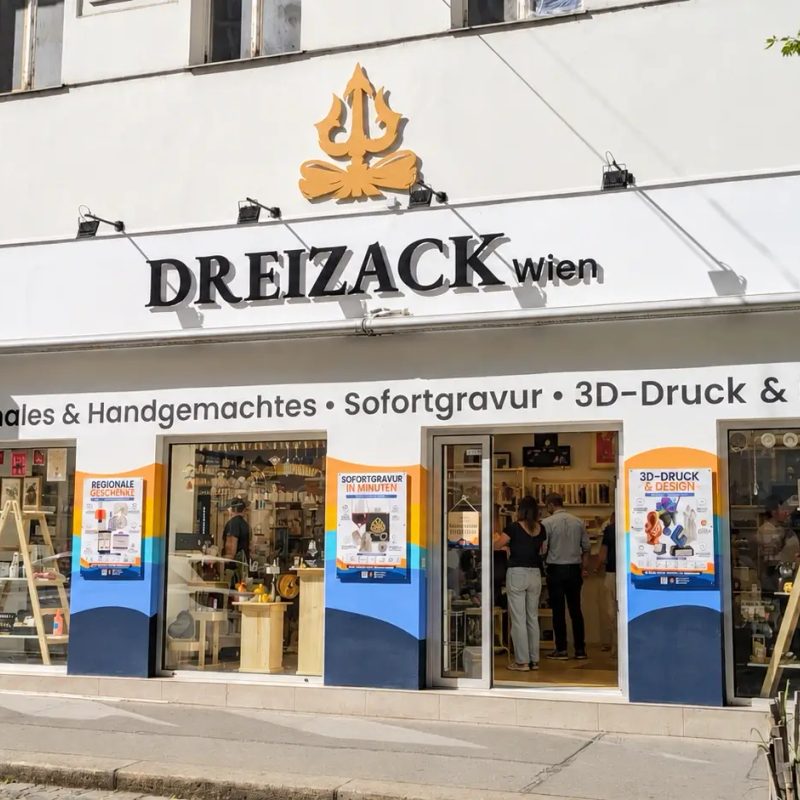 Das Geschäft von Dreizack Wien in der Josefstädter Straße: weiße Fassade mit goldenem Dreizack-Zeichen über dem Schriftzug Dreizack wien, davor der offene Eingang