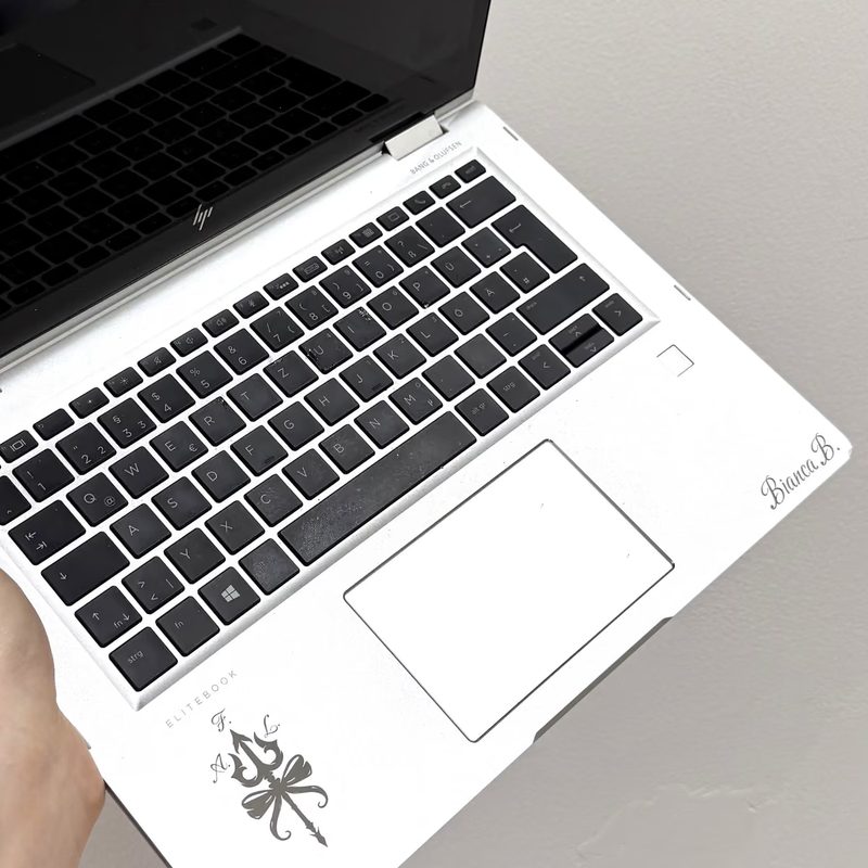 Ein aufgeklappter Laptop mit einem fein gravierten Namenszug auf der Handballenauflage