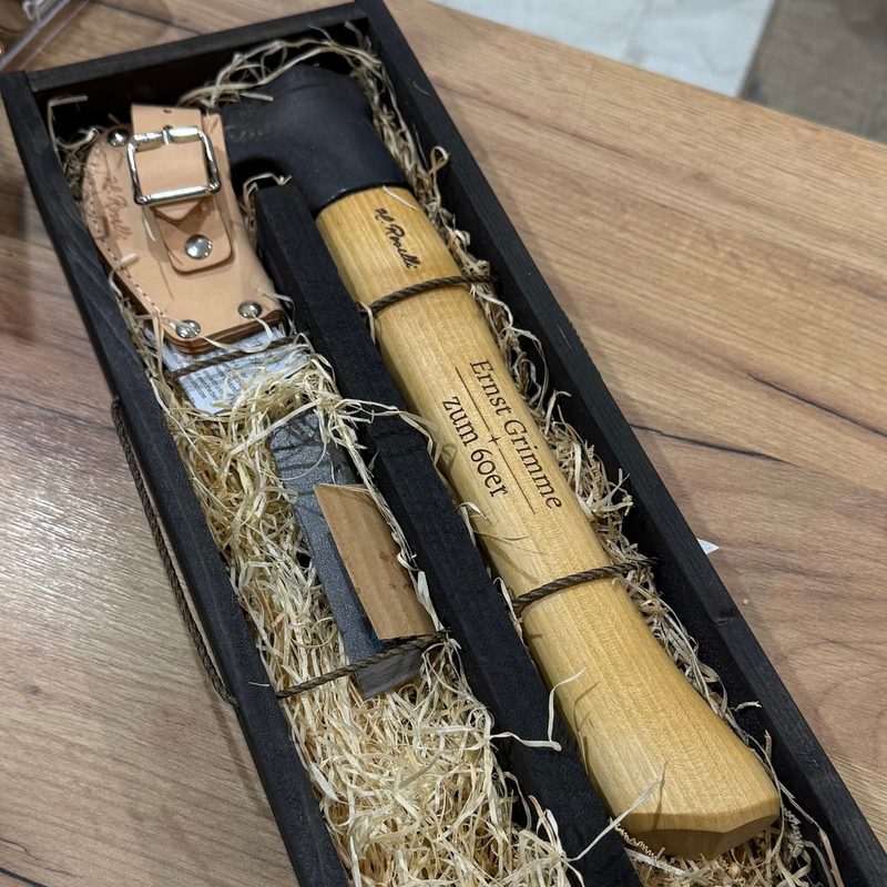 Ein Messerset in einer Holzkiste mit graviertem Deckel, daneben eine gravierte Holzschatulle