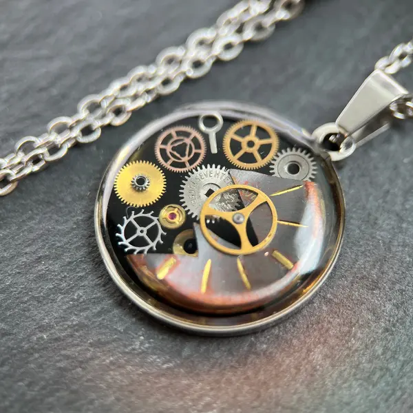 Silberne Halskette mit rundem Anhänger voller goldener und silberner Zahnräder