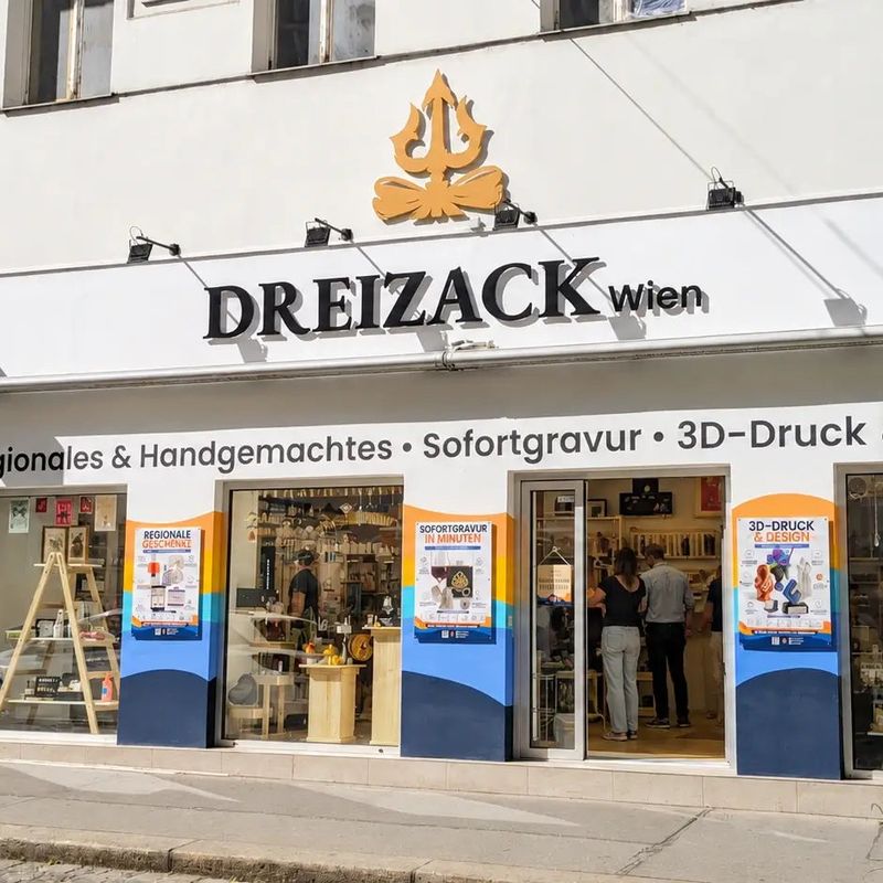 Das Geschäft von Dreizack Wien in der Josefstädter Straße 58 von außen, mit dem goldenen Dreizack mit Schlaufe über dem Schriftzug